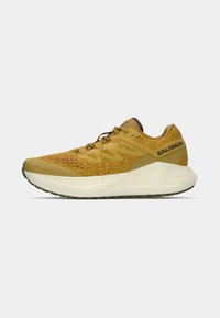 Os sapatos de corrida Salomon apresentam um cabedal texturizado amarelo, biqueira reforçada e uma sola branca acolchoada com um padrão de aderência robusto.
