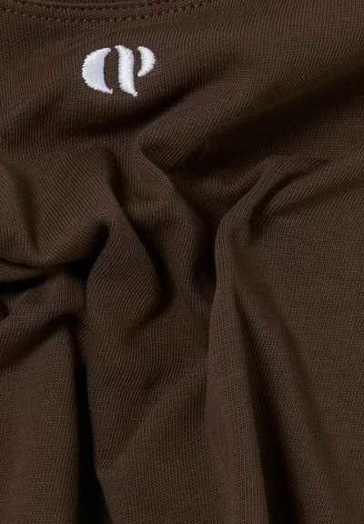 Tissu marron avec une texture lisse et douce, comportant un logo brodé blanc. Le matériau présente un motif de tricot fin et uniforme.