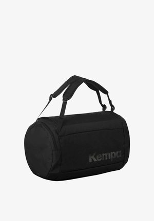 Schwarze zylindrische Reisetasche mit doppelt gepolsterten Schulterriemen, seitlicher Reißverschlusstasche und "Kempa"-Logo auf der Vorderseite.