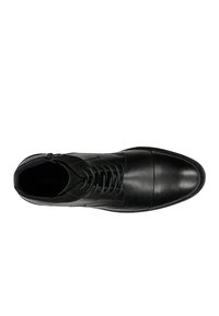 Stivale alla caviglia in pelle nera con punta arrotondata, chiusura con lacci e zip laterale. Texture liscia con una finitura opaca a contrasto.