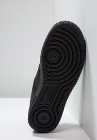 Černé tenisky s texturovanou gumovou podrážkou. Podešev má kruhové vzory a hluboké drážky pro lepší přilnavost. Boční strana má hladký povrch.