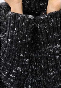 Schwarzer Strickpullover mit gesprenkelten weißen und grauen Fasern. Die gerippten Bündchen zeigen ein strukturiertes Muster und vermitteln ein weiches, gemütliches Erscheinungsbild.