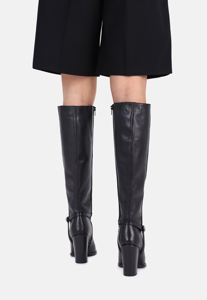 Knöchelhohe schwarze Lederstiefel mit glatter Textur, Blockabsätzen, seitlichen Reißverschlüssen und dekorativen Knöchelriemen für zusätzliche Details.