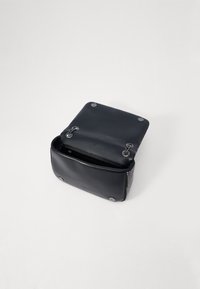 Borsa in pelle nera con una forma strutturata, una texture liscia, chiusura magnetica e un'elegante ferramenta in argento su un lato.