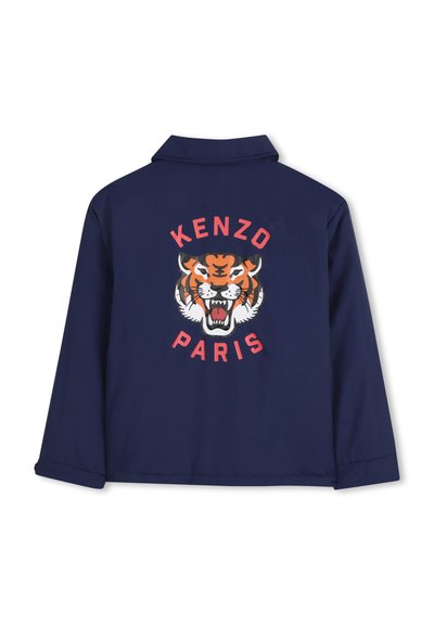 Marineblauwe jas met een grote tijgerafbeelding in oranje, zwart en wit; "KENZO" en "PARIS" gedrukt boven en onder het ontwerp.