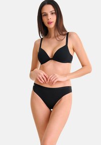Ensemble de lingerie noir comprenant un soutien-gorge triangle rembourré et un slip bikini assorti, fabriqué en tissu lisse avec des détails de logo sur la bande.
