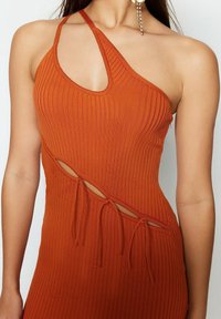 Robe sans manches à côtes en orange brûlé avec un décolleté asymétrique et des découpes à la taille, dotée de détails à nouer réglables.