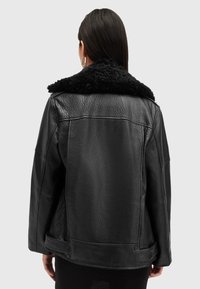 Μαύρο δερμάτινο μπουφάν με υφή και μαύρο γούνινο γιακά. Διαθέτει άνετη εφαρμογή και κουμπώματα στη μέση.