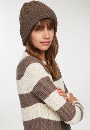 Berretto lavorato a maglia marrone con texture a costine e motivo intrecciato. Maglione a righe in crema e marrone, con ampie righe orizzontali.