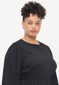 Black dress with long puffed sleeves, lightweight fabric, rounded neckline, and gathered waistline. Simple design with a smooth texture.