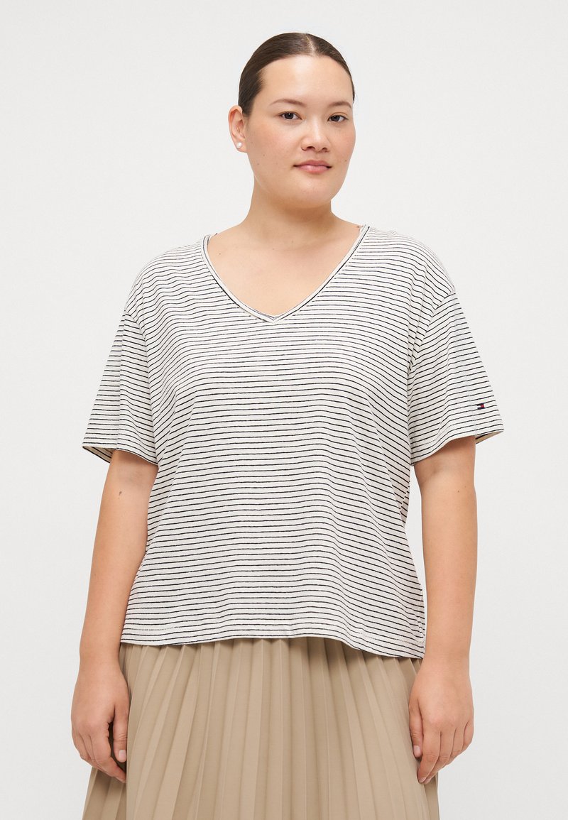 Stripet kortermet V-hals T-skjorte i lys beige med marineblå striper. Myk stoff; avslappet passform. Liten logo på venstre arm.