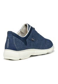 Zapatilla textil azul con suela blanca, que presenta un diseño sin costuras y acentos de costura sutiles. Incluye un logo en el talón.