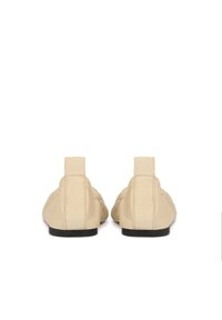 Beige Lederballerinas mit abgerundeter Zehenpartie, strukturiertem Obermaterial, niedrigem Profil und ohne sichtbare Schnürsenkel oder Verschlüsse; mit einer glatten schwarzen Sohle.