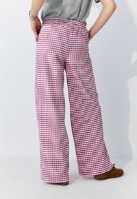 Wijdvallende broek met een rood-wit geblokt patroon, voorzien van een elastische tailleband en een lichtgewicht stof, met een ontspannen silhouet.