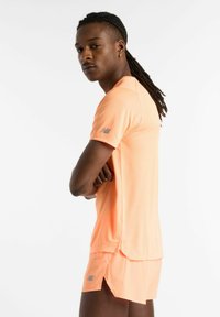 Short-sleeve athletic shirt and shorts in fluorescent orange, made from lightweight fabric, featuring mesh texture and logo detail on sleeve.