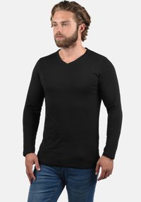 Zwart T-shirt met lange mouwen en V-hals, gemaakt van zachte stof, met een aansluitende pasvorm, een gladde textuur en zonder zichtbare patronen of accenten.