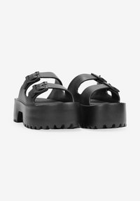 Sandali neri con due fibbie regolabili, suola platform spessa e bordo rigato. Texture in pelle liscia e design open-toe.