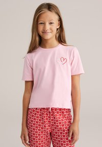 T-shirt a maniche corte rosa chiaro con ricamo di un cuore rosso e bianco sul lato sinistro del petto, realizzato in morbido cotone.
