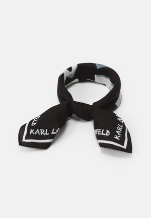 Czarnobiały wzorzysty szalik na szyję zawiązany w supeł z tekstem "KARL LAGERFELD" na końcach na białym tle.