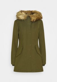 Parka vert olive avec capuche bordée de fourrure, fermeture à boutons-pression à l'avant, poches latérales et tissu texturé. Présente une silhouette ajustée.