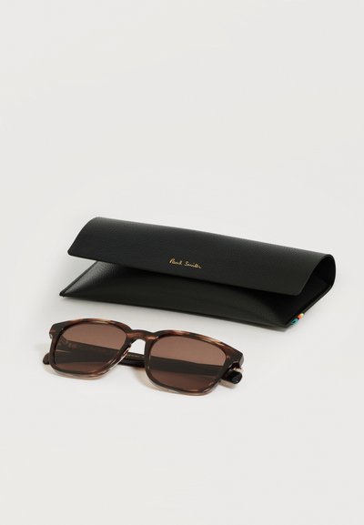 Lunettes de soleil rectangulaires marron avec montures écaille à côté d'un étui texturé noir avec le logo doré « Paul Smith ».