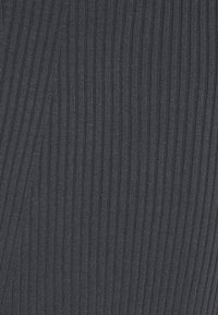 Tissu tricoté gris foncé à côtes avec des lignes texturées verticales et de légers plis diagonaux.