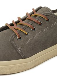 Sneaker in camoscio marrone con suola in gomma testurizzata, lacci gialli e marroni a contrasto e occhielli metallici. Design semplice e minimalista.