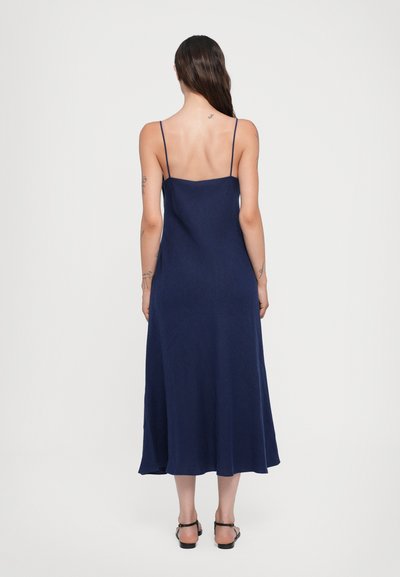 Vestido midi azul marino con tirantes finos, un corsé ajustado y una falda fluida. Tejido suave y diseño minimalista.