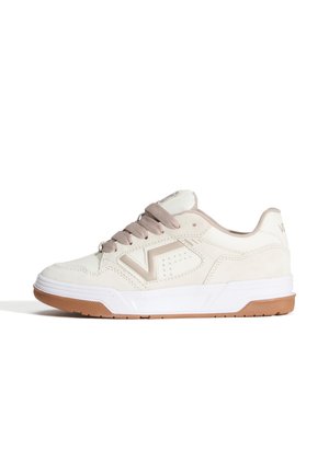 Zapatilla blanca de ante con detalles en beige claro, puntera redonda y un logo lateral texturizado. Cuenta con una suela acolchada y cordones tradicionales.