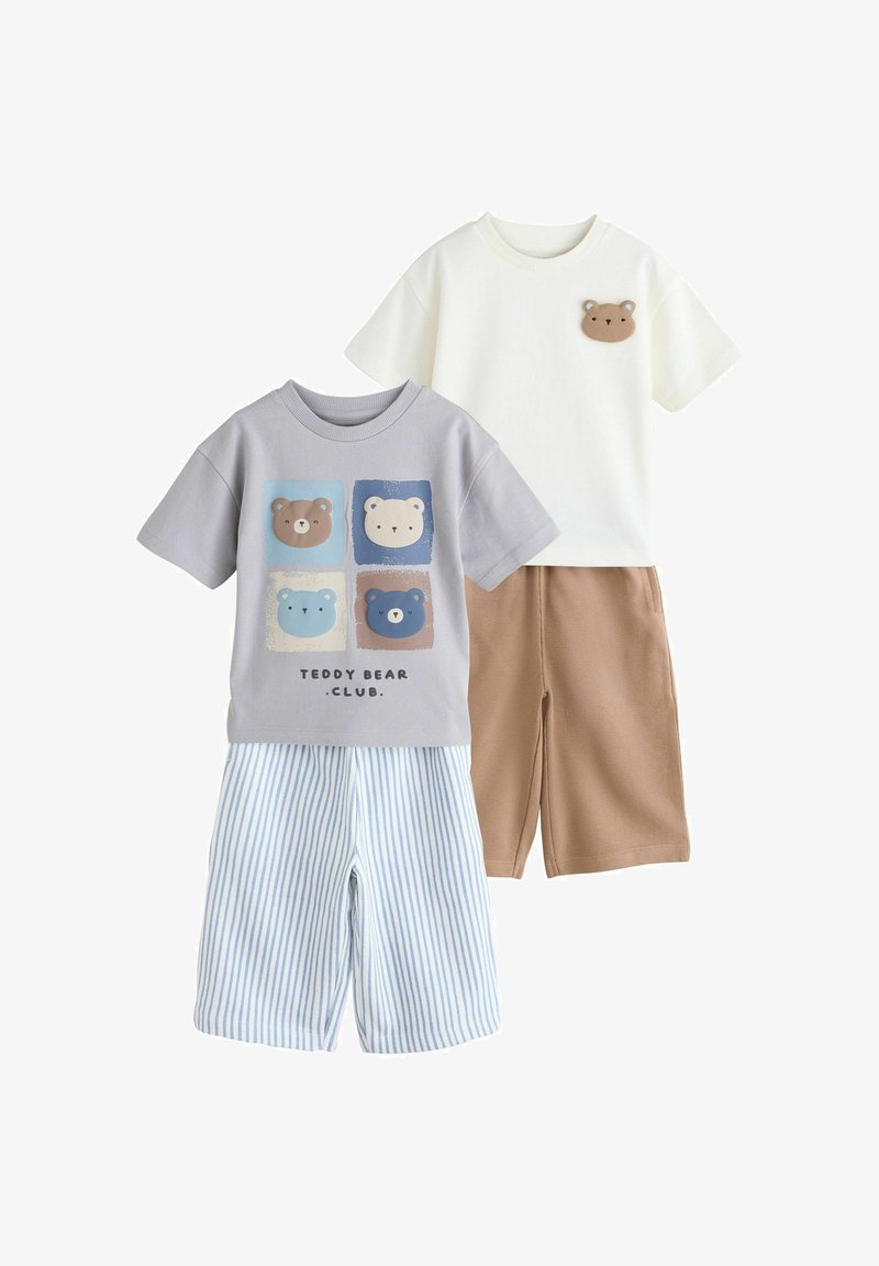 Deux tenues pour tout-petits : l'une avec un t-shirt imprimé d'un ours en peluche gris et un short à rayures bleues, l'autre avec un t-shirt blanc orné d'un patch ours en peluche et un short marron.
