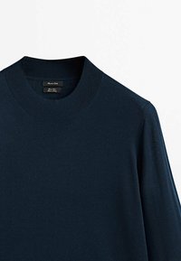 Marineblauer Strickpullover mit rundem Ausschnitt, der eine glatte Textur und einen gerippten Kragen aufweist. Etiketten sind im Halsbereich sichtbar.