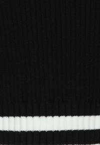 Tissu noir à côtes avec une rayure horizontale blanche en bas. La texture est douce avec des lignes verticales bien marquées.