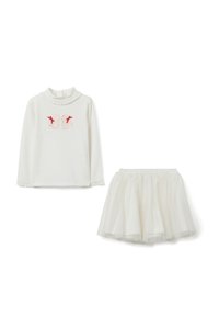 Top bianco a maniche lunghe con applicazioni di farfalle e fiocchi rossi, abbinato a una gonna di tulle bianca glitterata per un bambino.