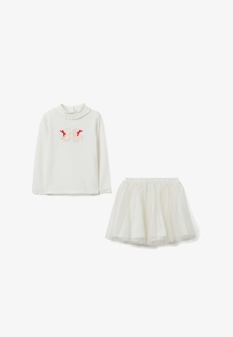 Top bianco a maniche lunghe con applicazioni di farfalle e fiocchi rossi, abbinato a una gonna di tulle bianca glitterata per un bambino.