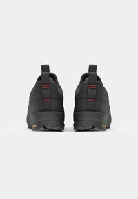 Black outdoor shoes featuring a rounded design, textured upper, red accents, pull tabs, and a Vibram outsole for enhanced grip.