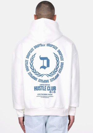 Weiße, übergröße Kapuzenjacke mit einem blauen Grafikdesign auf dem Rücken, das ein Kranzdesign, den Buchstaben 'D' und den Text "LIMITED EDITION HUSTLE CLUB" zeigt.