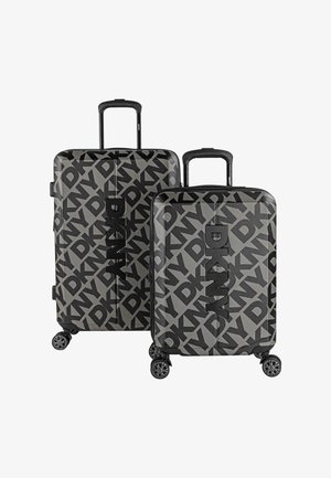 Dos maletas rígidas en gris con un patrón gráfico negro y una gran marca DKNY. Cada una tiene cuatro ruedas y un asa retráctil.