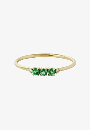 Anillo de oro con una banda delgada que presenta tres piedras preciosas verdes y dos pequeñas piedras transparentes, engastadas en garras, que muestran un diseño simple.