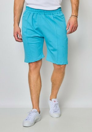 Shorts en coton bleu clair avec une taille élastique, des poches latérales et une coupe décontractée, présentant des coutures surpiquées et une texture lisse.