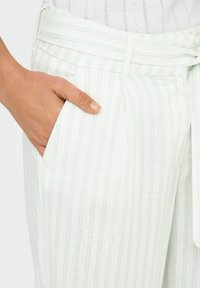 Białe spodnie w paski wykonane z lekkiego materiału z paskiem do związania, z bocznymi kieszeniami i subtelnymi niebiesko-zielonymi paskami dla lepszego efektu.