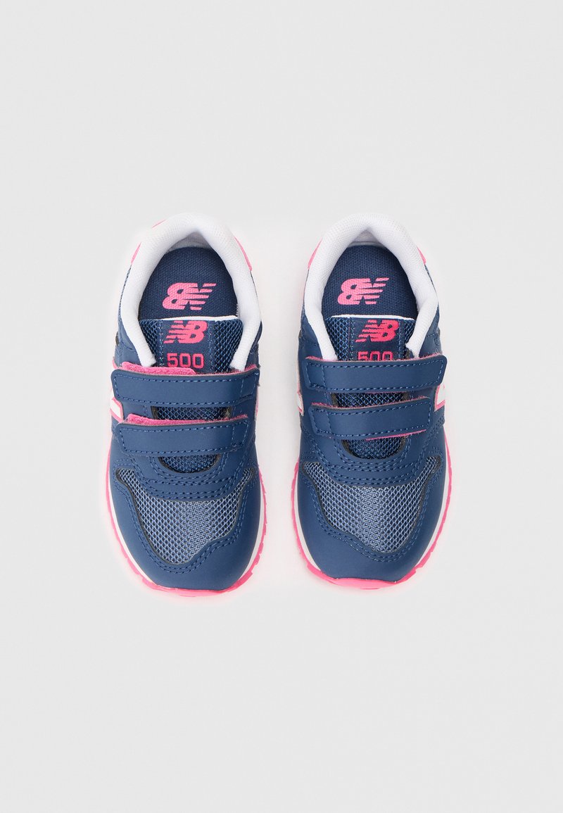Zapatillas New Balance azul marino con material de malla y sintético, correas de Velcro dobles, acentos en rosa y un interior acolchado blanco.