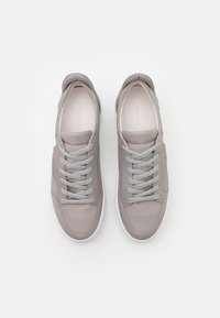 Sneaker in pelle grigia con una texture liscia, lacci grigi chiari, suole in gomma bianca e design minimalista. Nessun motivo o logo visibile.