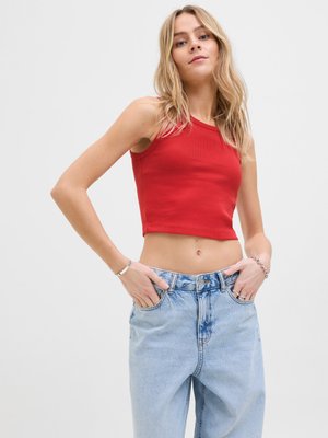 Rød ribbestrikket kort tanktopp kombinert med lyseblå høytlivsjeans. Toppens har smale stropper og en tettsittende design med en glatt tekstur.