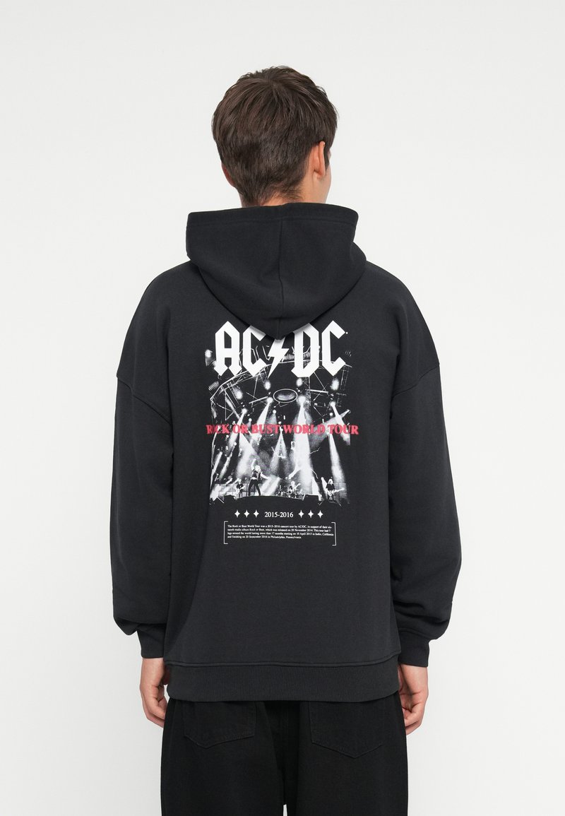 Fekete kapucnis pulóver, nagyméretű fehér AC/DC logóval, koncertgrafikával, és a hátsó oldalon a "Rock or Bust World Tour" felirattal.