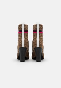 Bottines marron à motifs avec une tige texturée, un talon haut noir et une languette de tirage arrière blanche ornée d'une bande accent fuchsia et marron.