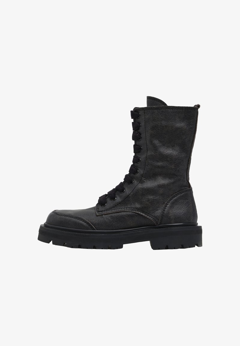 Czarny skórzany but bojowy do połowy łydki z grubą podeszwą z bieżnikiem i przednim wiązaniem na sznurówki, widoczny z zewnętrznej strony.