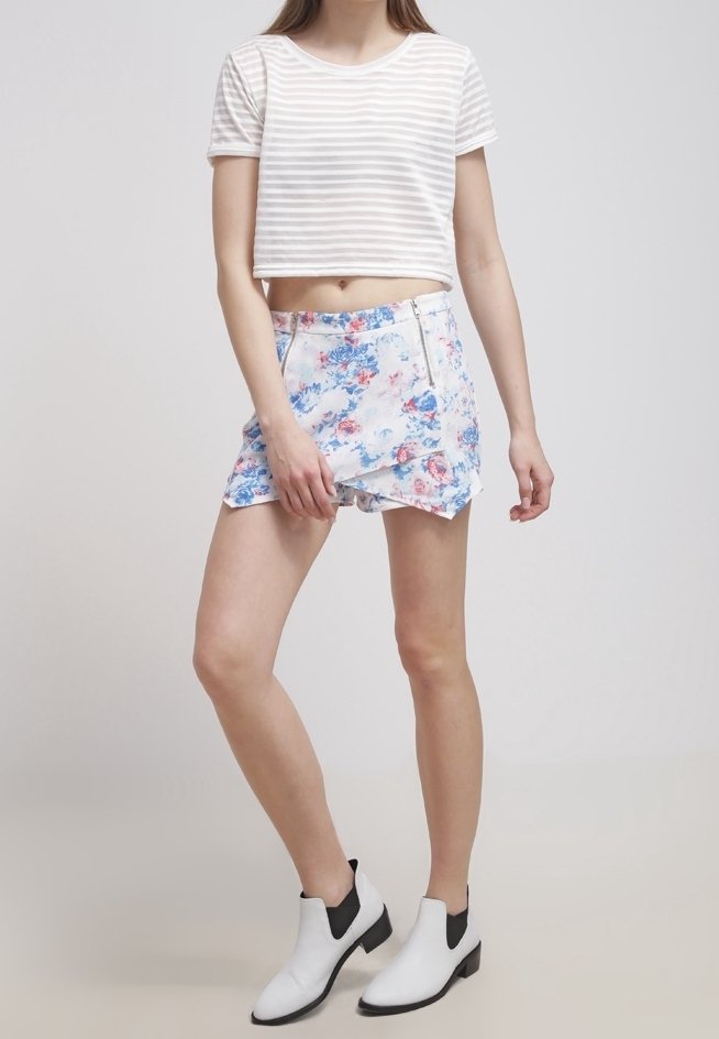 Haut court rayé blanc et gris, short à motif floral en bleu et rose, et bottines noires et blanches. Design simple et décontracté.