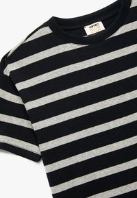 Czarna i szara w paski krótki rękaw t-shirt wykonany z materiału prążkowanego. Posiada okrągły dekolt z widocznym szwem oraz metką oznaczoną "Karton Kids."