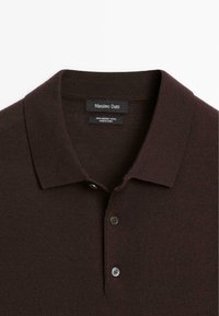 Bruine polo gemaakt van 100% merinowol, met een kraag, een manchettopening met twee knopen en een textuur gebreid patroon.