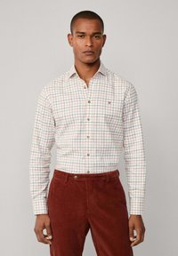 Witte button-up shirt met een rood en groen ruitpatroon, voorzien van knoopmanchet en een kleine geborduurde accent, gedragen met brown corduroy broek.
